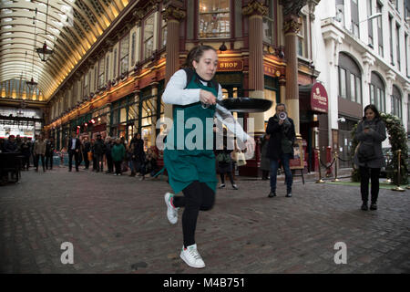 Mardi Gras festivités comme des concurrents s'alignent pour le Leadenhall Market Crêpes Race le 13 février 2018 à Londres, Royaume-Uni. Les équipes de travailleurs de la ville à l'extérieur de la taverne de l'agneau s'attaquer au cours de 25 m, la compétition pour gagner le trophée convoité poêle quand ils leur chemin autour de l'historique du marché du 14ème siècle. Banque D'Images