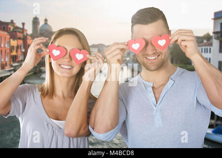 Smiling Young Couple couvrant leurs yeux avec papier Banque D'Images