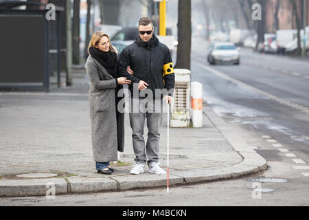 Jeune femme aider aveugle avec Stick blanc sur la rue Banque D'Images