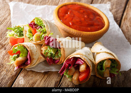 Burrito fait maison avec la Turquie, la laitue et la tomate close-up sur papier et le ketchup sur la table horizontale. Banque D'Images