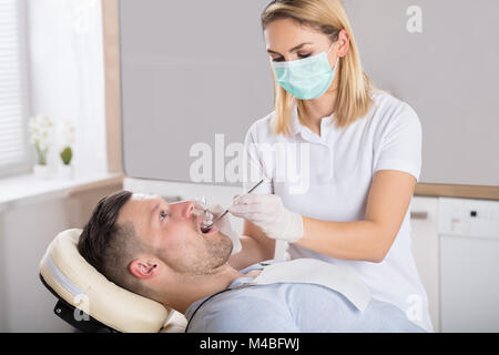 Patient de sexe masculin ayant ses dents examinées par femme dentiste dans une clinique Banque D'Images