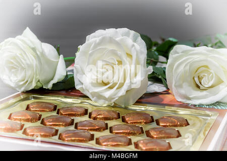 Des roses blanches et des chocolats en cadeau. Banque D'Images