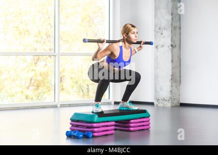 Femme blonde sit-ups, l'étape d'exécution le barbell avec plate-forme. Studio shot Banque D'Images