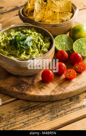 Bol de trempette avec des croustilles au guacamole et tomates cerises limes Banque D'Images