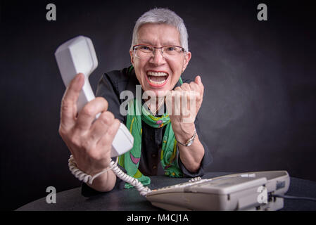 Service terrible colère, senior woman yelling at téléphone Banque D'Images