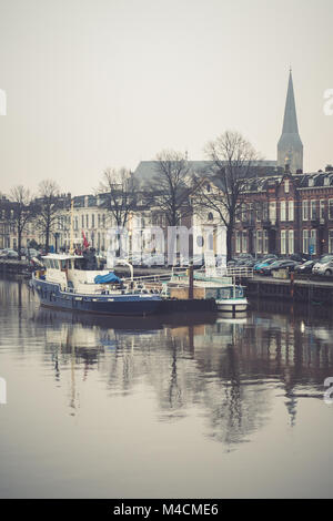 KAMPEN, Pays-Bas - 15 décembre 2017 : bateaux amarrés le long de la rivière IJssel à Kampen sur un jour d'hiver gris. Dans l'arrière-plan le monumental Bov Banque D'Images