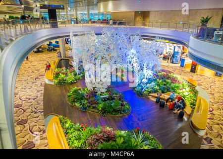 Singapour - circa 2016, août : au-dessus de la vue des personnes non identifiées, assis sur une des chaises dans un petit jardin avec des plantes à l'intérieur de l'aéroport Singapour Changi. L'aéroport Changi de Singapour est le principal aéroport civil pour Singapour Banque D'Images