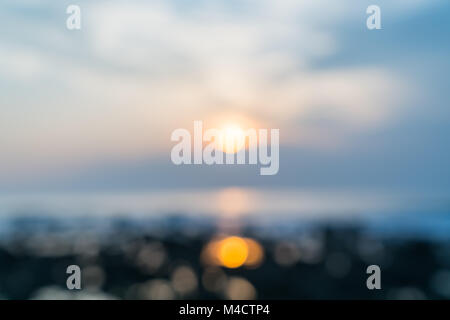 Defocued Résumé lueur brillante de soleil derrière cloads reflétée dans un matin brumeux sur rockpools ovelooking fond paysage côtières rocheuses. Banque D'Images