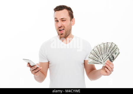 Image de beau jeune homme isolés sur fond blanc à l'aide de téléphone mobile. Appareil photo à la détention de monnaie. Banque D'Images