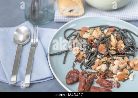 Spaghetti à l'encre de seiche avec des fruits de mer et les tomates Banque D'Images