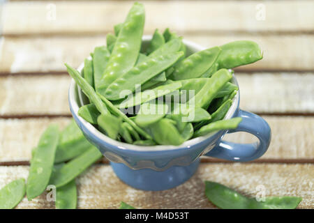 Pois sugar snap sur fond bleu rustique et tasse Banque D'Images