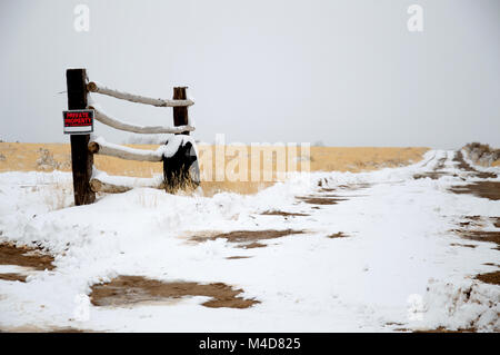 Un ancien pneu appuyé contre un poteau de clôture dans le désert de l'Utah patché avec la neige. Banque D'Images