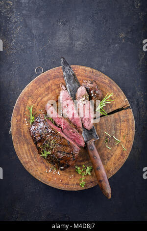 Steak de chevreuil sur la vieille planche à découper Banque D'Images