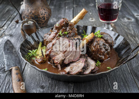 Knuckles l'agneau avec légumes en sauce au vin rouge Banque D'Images