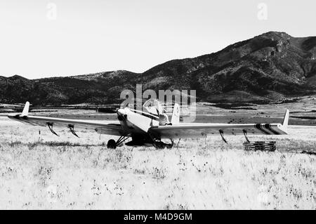 Un seeder jaune avion a atterri dans le désert de l'Utah avec le pilote assis sur les ailes en noir et blanc. Banque D'Images