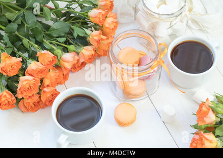 Macarons Orange, tasse de café et des roses fraîches Banque D'Images