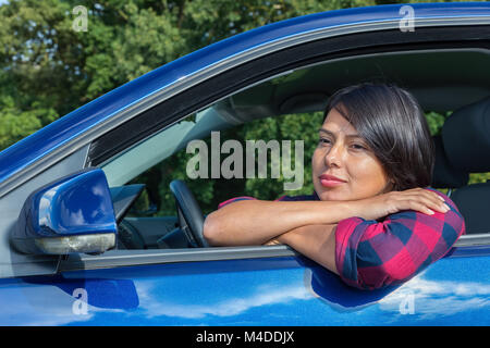 Femme colombienne profitant du soleil derrière la roue de voiture Banque D'Images