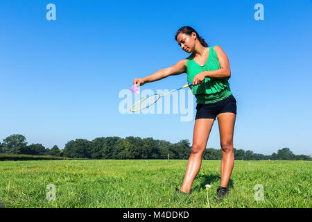 Femme servir avec raquette de badminton et de navette à l'extérieur dans l'herbe Banque D'Images