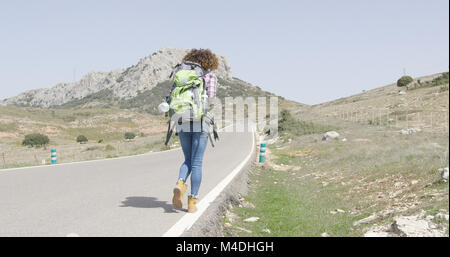 Vue arrière de woman walking down road Banque D'Images