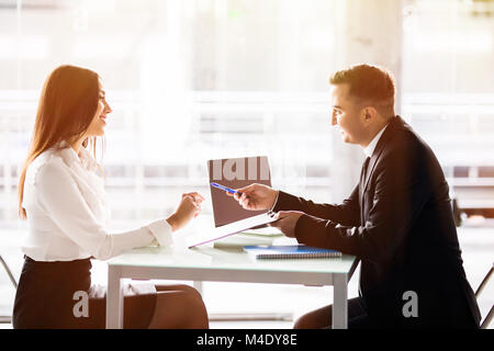 L'homme d'affaires et femme d'affaires signer un contrat. Satisfait les conditions de prêt woman singing contrat lorsque assis à 24 en face de la banque employé de sexe masculin Banque D'Images