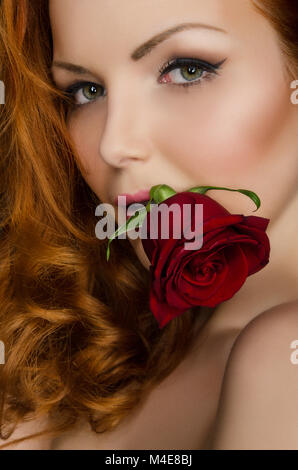 Femme aux longs cheveux rouges rose tient dans sa bouche Banque D'Images
