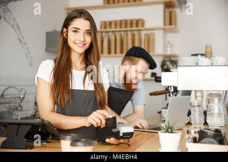 - Concept d'affaires café barista femelle magnifique service de paiement pour les dons par carte de crédit du client et souriant tout en travaillant dans le comptoir de café moderne. Banque D'Images