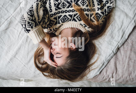 Smiling woman lying on bed Banque D'Images