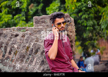 Jeune homme à la chemise à carreaux à la recherche de téléphone cellulaire, Pune, Maharashtra. Banque D'Images