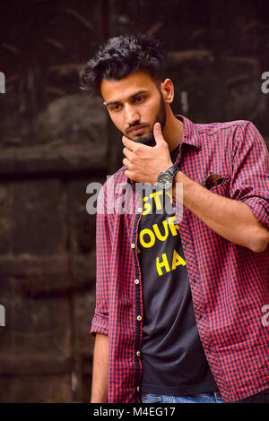Jeune homme à la chemise à carreaux en tenant son menton, Pune, Maharashtra. Banque D'Images