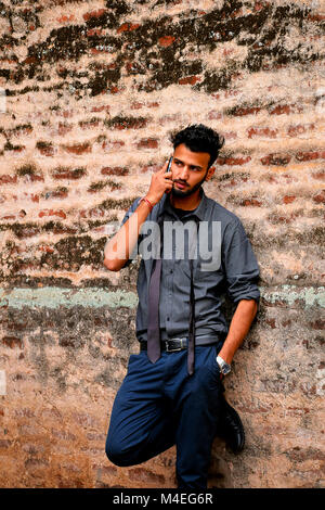 Jeune homme habillé de noir et chemise cravate avec téléphone cellulaire, Pune, Maharashtra. Banque D'Images