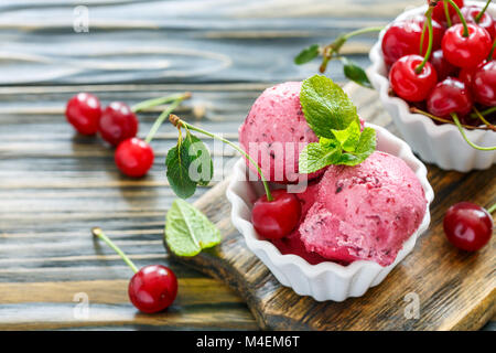 Des tasses avec glaces faites maison et de cerises mûres. Banque D'Images