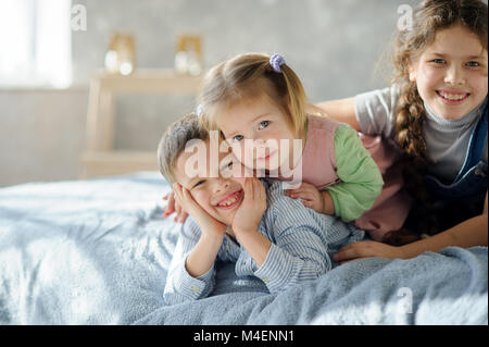 Deux soeurs et un frère. Trois enfants de la même famille sont allongés sur le lit. Banque D'Images