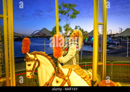 Heureux libre équitation sur cheval blanc de carrousel, à l'Esplanade à Perth, Australie occidentale. Elizabeth Quay par nuit. Activités et concept. Banque D'Images