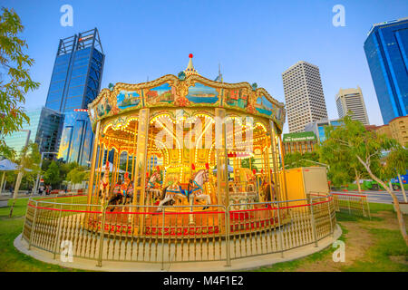 Perth, Australie - Jan 6, 2018 : Carrousel Vénitien traditionnel à Elizabeth Street, Perth, WA. Esplanade avec les gratte-ciel modernes du quartier central des affaires sur l'arrière-plan. Blue Hour shot. Scène urbaine. Banque D'Images