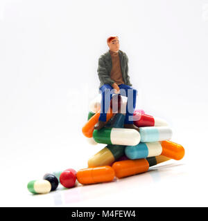 L'homme, miniature, figurine, assis sur les produits pharmaceutiques Banque D'Images