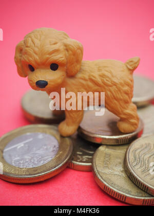 2018 Année du chien. Mignon petit chien sur fond rouge à côté d'une pile de symbolique de la chance 8 pièces d'or. Banque D'Images