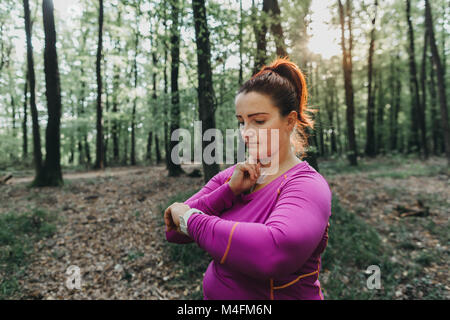 Portrait d'une grande taille femme jogger mesurer son pouls après un jogging dans un parc. Banque D'Images