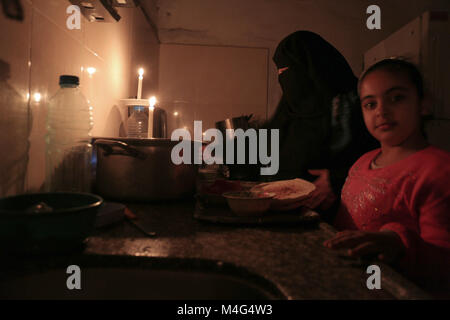 Gaza, Territoires palestiniens. 16 Février, 2018. La mère palestinienne assiste à un dîner aux chandelles à leur maison de fortune dans le camp de réfugiés de Rafah, dans le sud de la bande de Gaza, le 15 février 2018. L'entreprise de production électrique de Gaza dans la bande de Gaza a cessé de fonctionner le 15 février 2018 en raison d'un manque de carburant, le fonctionnaire a déclaré, en ce qui concerne a augmenté au cours de l'aggravation de l'état humanitaire dans l'enclave palestinienne. Plus de Palestiniens dans la bande de Gaza utilisent des piles, des générateurs ou des bougies pour éclairer leurs maisons. Les habitants de Gaza, qui abrite 1,8 million de personnes de subir une panne d'électricité 21 par jour. © Banque D'Images