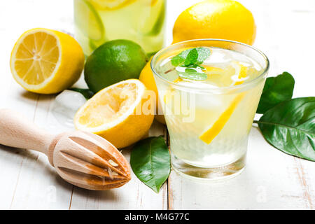 Limonade naturelle avec du citron, de lime et de menthe avec du citron et de l'aléseur de feuilles d'arbres sur une table en bois blanc Banque D'Images