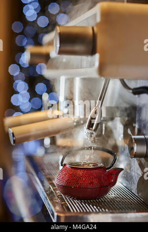 Faire un thé dans une tetsubin rouge avec une machine à café italienne classique. Banque D'Images