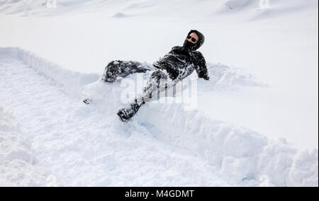 L'homme est de tomber dans la neige profonde. Concept de winterly conditions glissantes. Banque D'Images