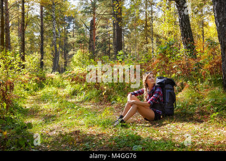 Jeune femme touristique avec un sac à dos assis en marge de la sentier de forêt. La Russie, la Sibérie, Salair Banque D'Images