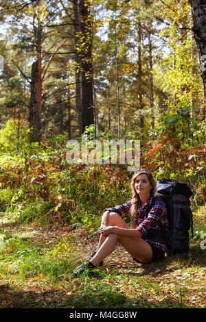 Jeune femme blonde touriste avec un sac à dos, assis à l'écart du chemin forestier. La Russie, la Sibérie, Salair Banque D'Images