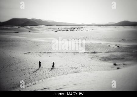 Deux personnes admirant l'étendue de sable se dérouler devant eux, parmi les dunes de sable de Fuerteventura, Las Canarias Banque D'Images