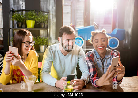 Amis assis avec téléphone dans le café Banque D'Images