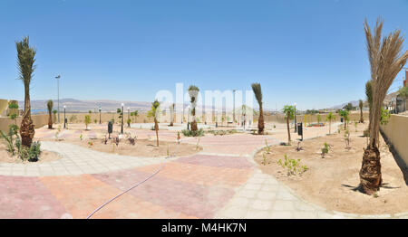 Un parc public à Aqaba en Jordanie qui est irriguée par l'eau de l'usine de traitement des eaux usées avec des palmiers et des lumières contre le ciel bleu Banque D'Images