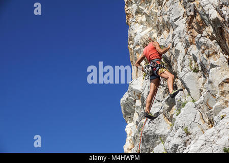 NAPLES , ITALIE -04 septembre 2017 : une femme athlétique et monte une montagne près de la mer sur une chaude journée d'été .mise à l'échelle du visage de roche est un sport pratiqué par de nombreuses personnes Banque D'Images