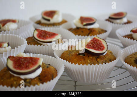 Des muffins cupcakes / formulaires en papier blanc avec des figues fraîches et un peu de crème fouettée sur le dessus. Banque D'Images