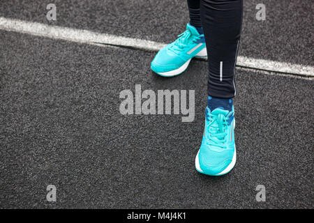 Les jambes de femme chaussures de course de couleur bleu dans l'article sur l'asphalte. Banque D'Images