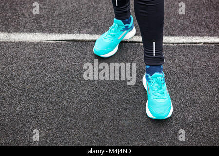 Les jambes de femme chaussures de course de couleur bleu dans l'article sur l'asphalte. Banque D'Images